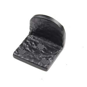 May include: Black metal door stop with a rounded top and a textured surface. It has three screws on the bottom.