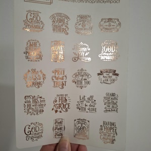 May include: A sheet of gold foil stickers with various inspirational quotes and phrases. The stickers are on a white background and feature a copper foil finish.