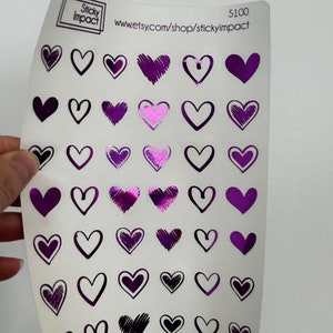 May include: A sheet of purple heart stickers with different designs. The stickers are on a white background. The sheet has the text "Sticky Impact" and "www.etsy.com/shop/stickyimpact" printed on it.