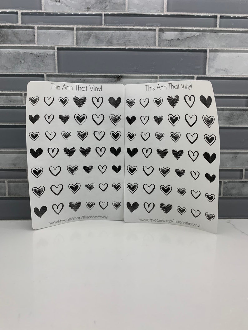 May include: Two sheets of white vinyl stickers with black heart designs. The sheets are labeled "This Ann That Vinyl" and include the website address "www.etsy.com/shop/thisannthatvinyl".