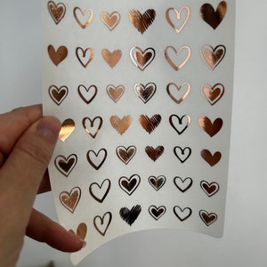 May include: A sheet of rose gold heart stickers with various designs. The sheet is white and has the text "Sticky Impact" and "www.etsy.com/shop/stickyimpact" printed on it. The price is listed as $100.