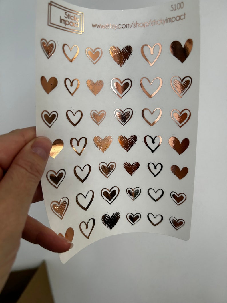 May include: A sheet of rose gold heart stickers with various designs. The sheet is white and has the text "Sticky Impact" and "www.etsy.com/shop/stickyimpact" printed on it. The price is listed as $100.