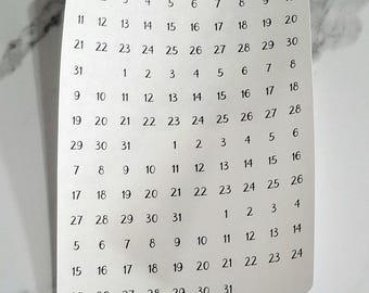 May include: A white sheet of paper with black numbers 1 through 31 printed in rows. The numbers are arranged in a calendar format. The paper has the text "Sticky Impact" and a website address printed at the top.
