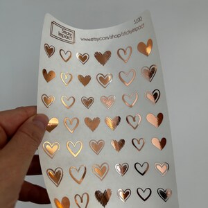 May include: A sheet of clear sticker paper with 40 rose gold heart stickers. The stickers are various sizes and styles. The sheet has the text "Sticky Impact" and "www.etsy.com/shop/stickyimpact" printed on it.  The price is listed as $100.
