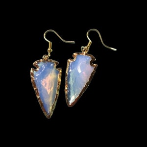 Könnte beinhalten: Ein Paar goldene Pfeilspitzen-Ohrringe mit schillernden Opal-Steinen. Die Ohrringe haben ein schlichtes, minimalistisches Design und sind perfekt für den Alltag.