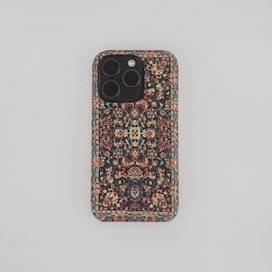 Może przedstawiać: Czarne etui na telefon z kolorowym wzorem dywanu. Etui ma wycięcie na obiektyw aparatu i czarną ramkę.