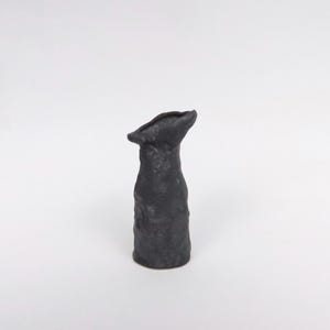 May include: A black ceramic vase with a textured surface and a wide opening at the top.