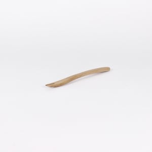 Könnte beinhalten: Ein Holzgriff mit einer gebogenen Form und einer spitzen Spitze. Der Griff ist hellbraun.
