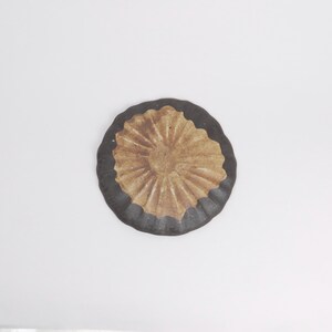 Puede incluir: Un plato redondo de cer&aacute;mica con un borde marr&oacute;n oscuro y un centro beige texturizado. El centro tiene un patr&oacute;n radial y un peque&ntilde;o dise&ntilde;o en relieve. El plato est&aacute; sobre un fondo blanco.