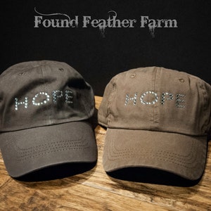 May include: Two brown baseball caps with the word "HOPE" spelled out in rhinestones.