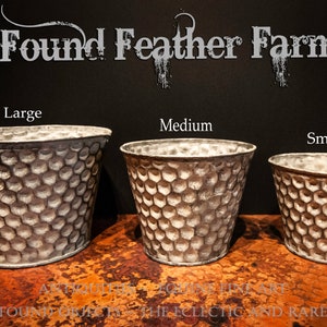 May include: Three galvanized metal planters in different sizes, labeled "Large", "Medium", and "Small". The planters have a textured, honeycomb-like pattern and are ideal for indoor or outdoor plants.