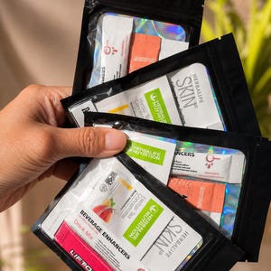 May include: Three black resealable pouches containing Herbalife Nutrition products. Each pouch features a clear window displaying various individual sachets labeled Beverage Enhancers, Herbal Tea Concentrate, Liftoff, and Skin Collagen Beauty.