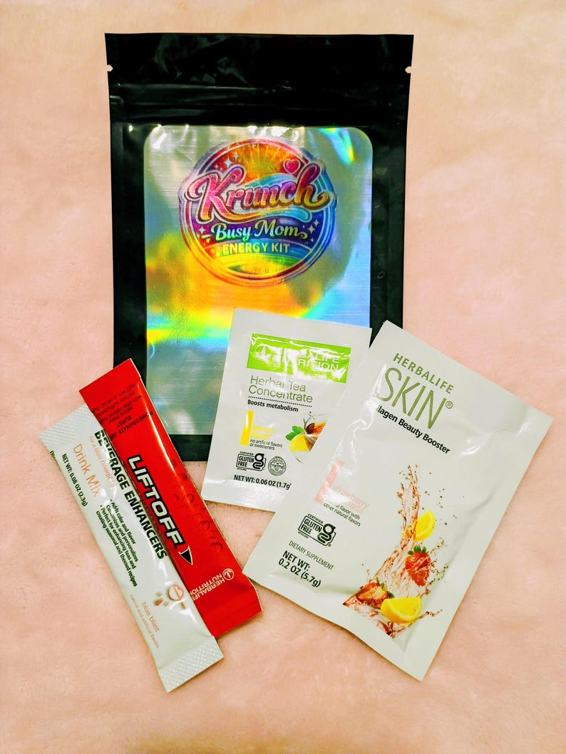 May include: A black holographic pouch labeled Krunch Busy Mom Energy Kit containing three individual packets: a red Liftoff beverage enhancer, a white Herbal Tea Concentrate packet, and a white Herbalife Skin Collagen Beauty Booster packet.