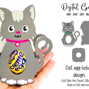 May include: A gray cat-shaped egg holder with a pink collar, holding a Cadbury Creme Egg. The design includes a tail and is made of paper. The image also shows a design for cutting files for Cricut, Silhouette, and Scan n Cut.
