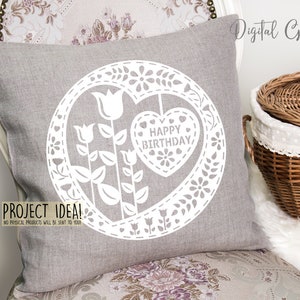 Puede incluir: Una almohada gris con un dise&ntilde;o de corte blanco en forma de coraz&oacute;n con el texto "Happy Birthday" en su interior. El coraz&oacute;n est&aacute; rodeado de flores y hojas. La almohada est&aacute; sobre una silla con un patr&oacute;n floral.