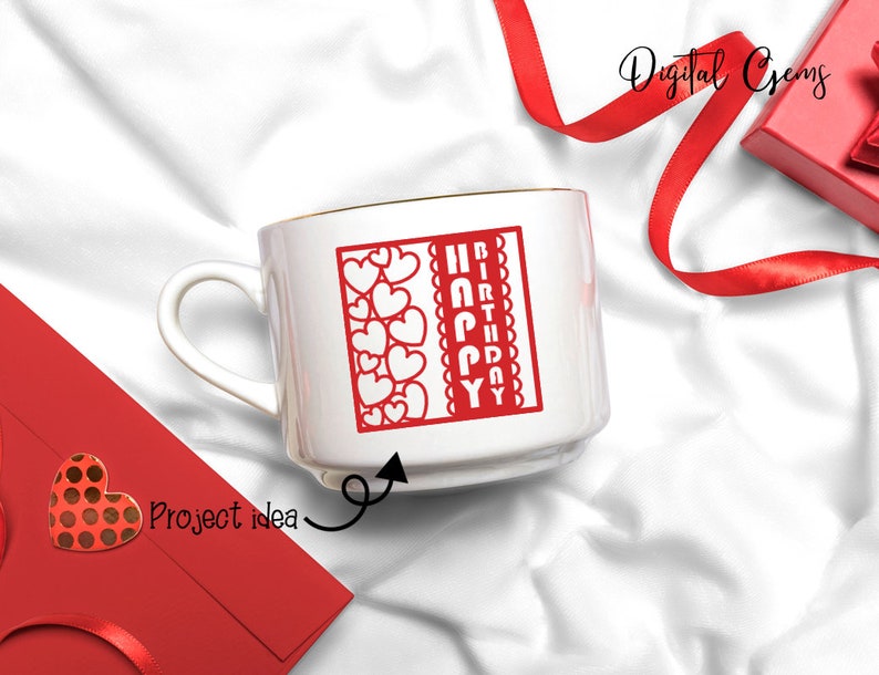Peut inclure: Une tasse en c&eacute;ramique blanche avec un bord dor&eacute;. La tasse pr&eacute;sente un motif rouge avec les mots "Joyeux anniversaire" et une bordure de c&oelig;urs rouges.