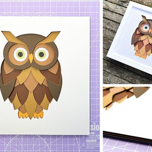 May include: A brown and gold paper owl with large eyes, framed in a white frame. The owl is layered and appears three-dimensional.