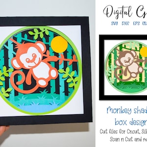 Può includere: Un file di taglio digitale per una scatola ombra di scimmia. Il design presenta una scimmia appesa a un ramo in un ambiente di giungla con foglie verdi e un sole giallo. Il testo "Digital Gems SVG DXF EPS FILES" e "Monkey shadow box design Cut files for Cricut, Silhouette, Scan n Cut and more!" è incluso nell'immagine.