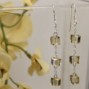 以下が含まれることがあります： シルバーのドロップイヤリング。各イヤリングに透明なファセットカットのキューブ型のクリスタルが3つずつ付いています。