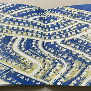 K&ouml;nnte beinhalten: Doppelseite aus einem Buch mit einer Luftaufnahme eines Wohngebiets. Der Druck verwendet ein blaues und gelbes Farbschema. Die H&auml;user sind gelb, die Stra&szlig;en wei&szlig; und der Hintergrund blau.