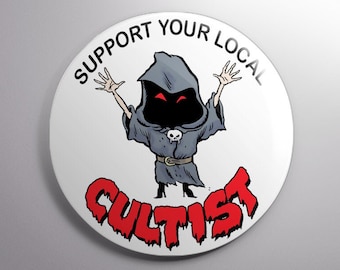 May include: A white button with a black border and the text "Support Your Local Cultist" in black. A cartoon image of a hooded figure with red eyes and a skull on its chest is in the center of the button.