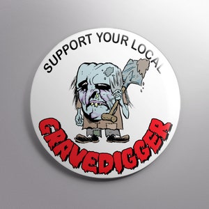 May include: White button with red text that says "Support Your Local Gravedigger". A cartoon illustration of a zombie-like figure holding a shovel is in the center.