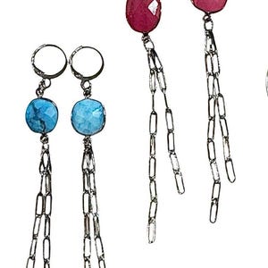 Puede incluir: Un par de pendientes con piedras turquesa y rojas, cada uno con una cadena de plata que cuelga de la parte inferior.