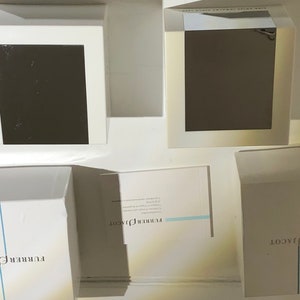 May include: Four white boxes with the text "FURRER JACOT" printed on them. The boxes are arranged in a square shape with one box in the center and three boxes surrounding it.