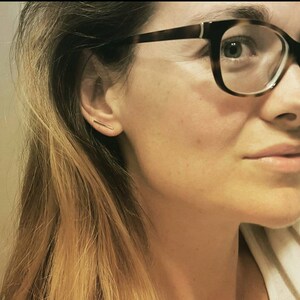 以下が含まれることがあります： 左耳に金の棒状のピアスをした眼鏡をかけた女性