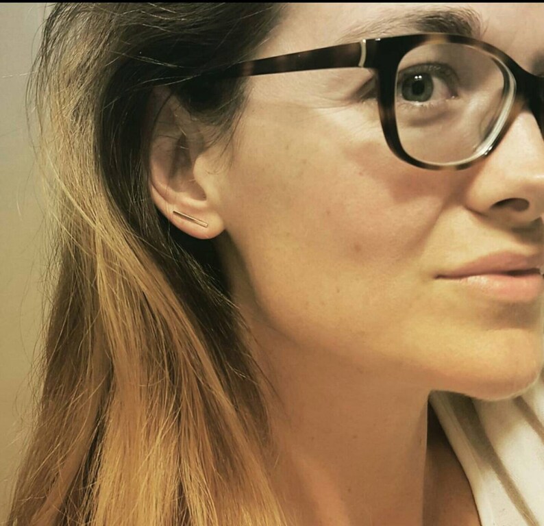 以下が含まれることがあります： 左耳に金の棒状のピアスをした眼鏡をかけた女性