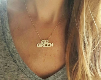 May include: A gold necklace with a pendant that says "GO GREEN" in block letters.