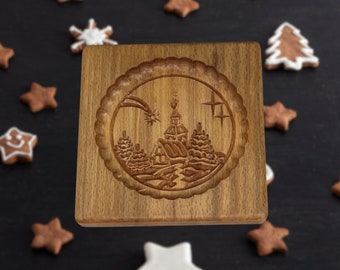 Op de afbeelding: Een houten kerstkoekjesvormpje met een gedetailleerd ontwerp van een kerk, bomen en een ster in een ronde lijst.