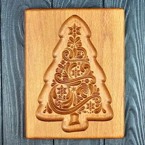 May include: A wooden Christmas tree cookie cutter with a detailed, intricate design. The cutter is made of light brown wood and has a natural finish.