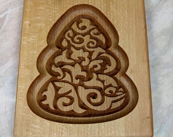 May include: A wooden cookie cutter in the shape of a Christmas tree with a detailed, intricate design.