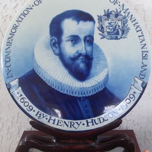 Puede incluir: Un plato de cer&aacute;mica azul y blanco que conmemora el descubrimiento de la isla de Manhattan por Henry Hudson en 1609, celebrado en 1909. El plato presenta un retrato de Henry Hudson y un escudo de armas con un barco.