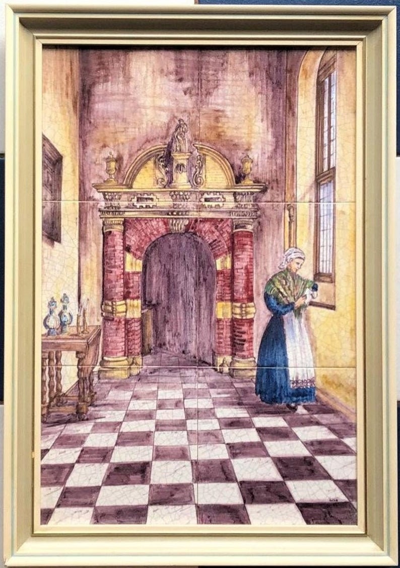 May include: A framed tile painting depicting a woman in a blue dress and white apron standing in a room with a checkered floor. The room has a large arched doorway with red brick columns and a wooden door. The woman is holding a fan in her hand.