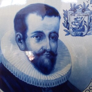 Pu&ograve; includere: Un piatto in ceramica blu e bianco con un ritratto di un uomo con un grande colletto bianco a pieghe. Il piatto presenta anche uno stemma con una nave e il testo "The Halcyon".