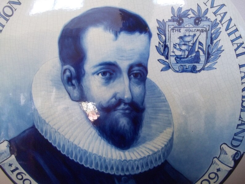 Pu&ograve; includere: Un piatto in ceramica blu e bianco con un ritratto di un uomo con un grande colletto bianco a pieghe. Il piatto presenta anche uno stemma con una nave e il testo "The Halcyon".