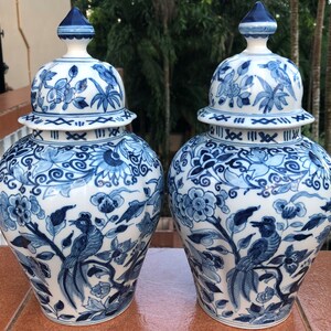 Puede incluir: Dos jarrones de jengibre de porcelana azul y blanca con intrincados dise&ntilde;os florales y de p&aacute;jaros. Los jarrones tienen una tapa con una banda decorativa alrededor de la parte superior.