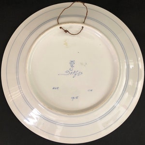 K&ouml;nnte beinhalten: Wei&szlig;e Keramikplatte mit blauem Rand und einer blauen Inschrift mit der Aufschrift "C.HOF" und "1915".