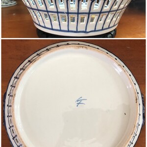 Może przedstawiać: Biało-niebieski ceramiczny kosz z ażurowym wzorem. Kosz ma okrągły kształt z płaską podstawą i dwoma uchwytami. Obręcz i uchwyty są ciemnoniebieskie, a wnętrze białe.