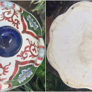 May include: A two-part ceramic serving dish with a floral and scroll design. The top bowl has a white base with red, green, and blue accents. The bottom is a white, scalloped dish.