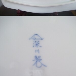 May include: A white ceramic plate with a blue and white Japanese kanji mark on the bottom. The mark is a stylized mountain with the kanji characters "窯変" and "窯" written below.