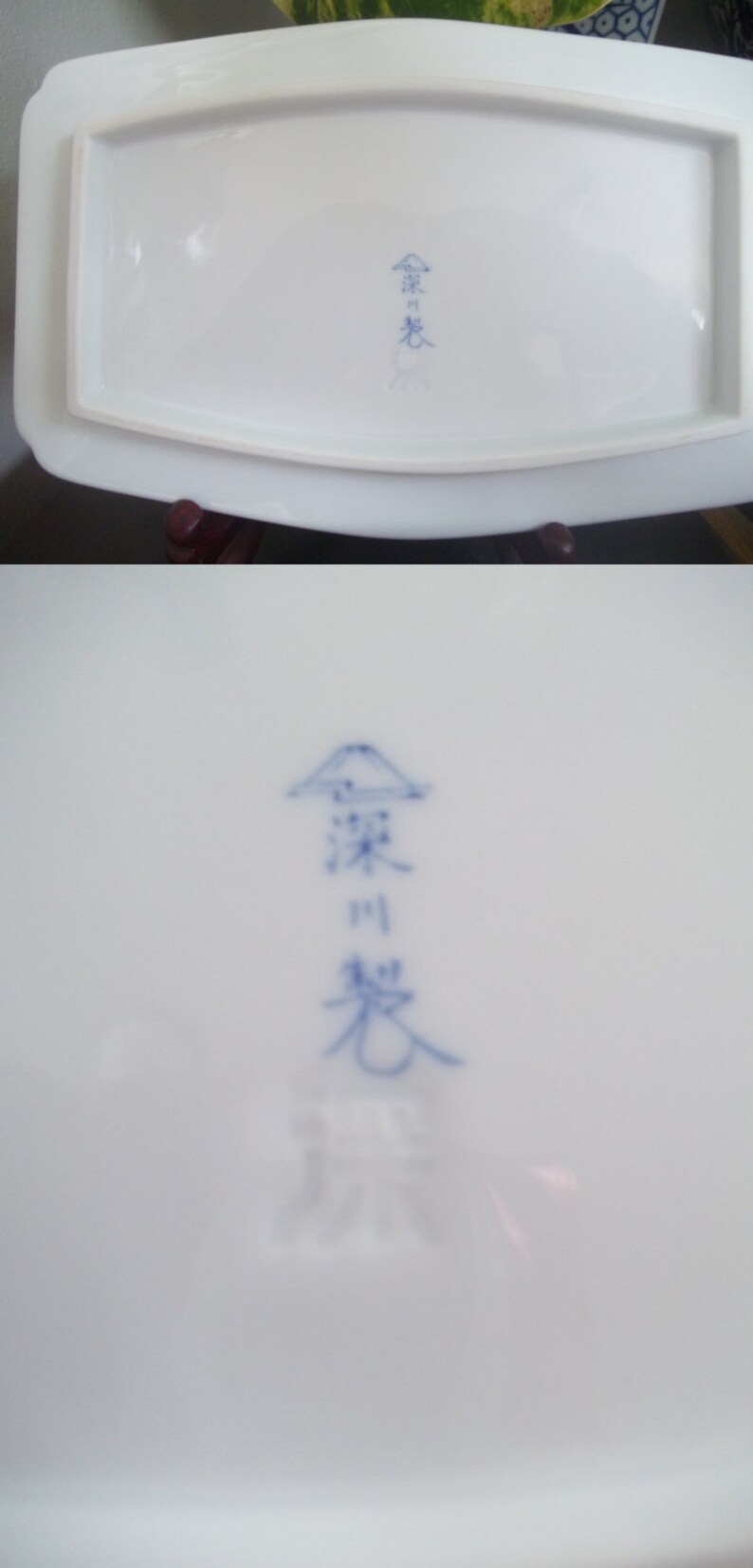 May include: A white ceramic plate with a blue and white Japanese kanji mark on the bottom. The mark is a stylized mountain with the kanji characters "窯変" and "窯" written below.