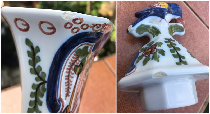 Puede incluir: Una jarra de cer&aacute;mica blanca con dise&ntilde;os florales pintados en azul, verde y marr&oacute;n. La jarra tiene un borde astillado y una peque&ntilde;a astilla en la base.