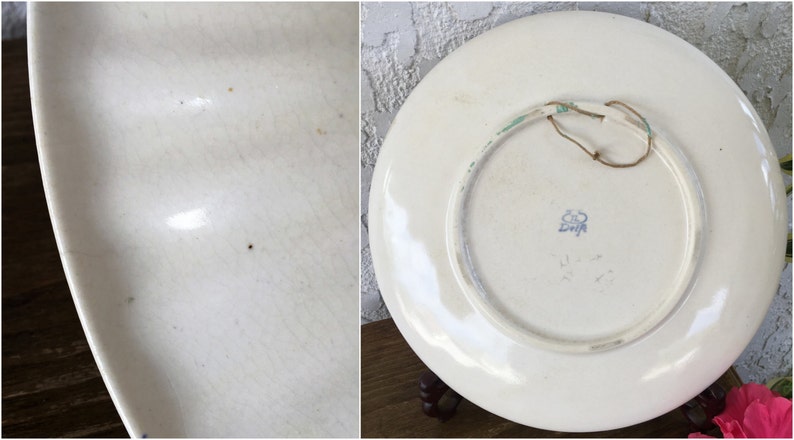 May include: White ceramic plate with a blue and green floral design. The back of the plate has a blue stamp that reads "Zwicker" and a hanging loop.