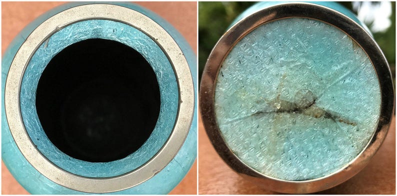 Pu&ograve; includere: Un vaso in ceramica blu turchese con un bordo argentato. Il vaso ha una crepa sul fondo e un bordo argentato intorno alla parte superiore.