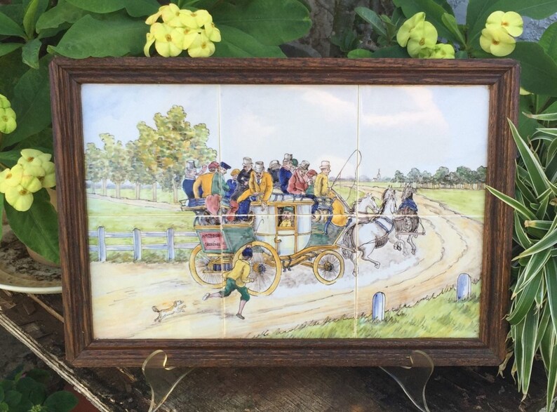 Puede incluir: Una pintura de azulejos enmarcada que representa un carruaje tirado por caballos con pasajeros que viajan por un camino de tierra. El carruaje est&aacute; lleno de personas vestidas con ropa colorida. La escena est&aacute; ambientada en un paisaje rural con &aacute;rboles y una cerca en el fondo.