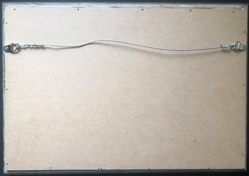 May include: The back of a framed picture with a wire hanging system. The frame is black and the backing is a light brown cardboard.