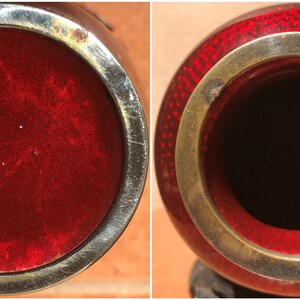 May include: A detailed view of a red and silver vase. The vase has a round shape with a silver rim and a red interior. The exterior is a deep red with a textured pattern. The vase is likely a decorative item.